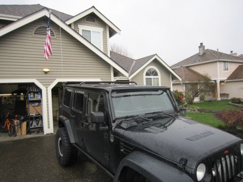 2008 Jeep Wrangler - A black Jeep Wrangler is parked in front of a suburban home on a cloudy day.