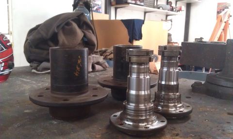 1978 Ford Bronco - Automotive axle shafts and hubs are laid out on a workbench, possibly for repair or replacement.