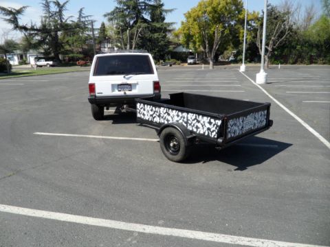 1994 Jeep Cherokee - A white Jeep Cherokee is parked in a lot, hitched to a black trailer with a unique camouflage design.
