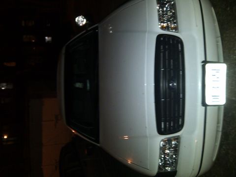 2000 Ford Crown Victoria - A white sedan is parked at night, with a light on its roof and a visible license plate.