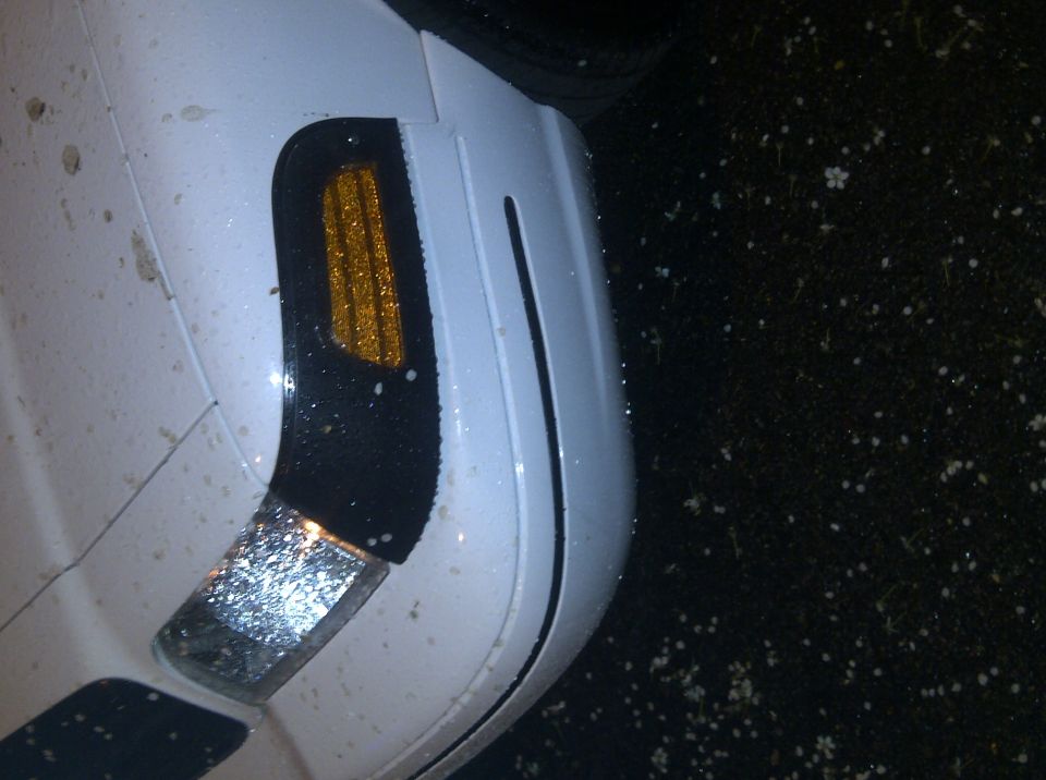 White car fender with amber turn signal light and chrome accent. 2000 Ford Crown Victoria