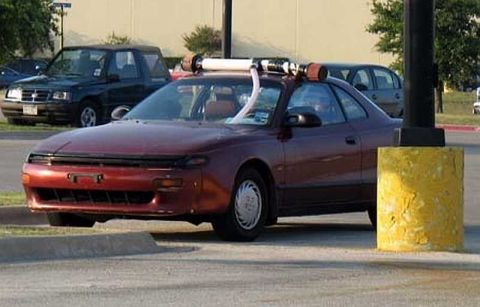 1997 Ford Taurus - A red coupe is parked with a snorkel attached to its roof rack, next to a dark SUV.