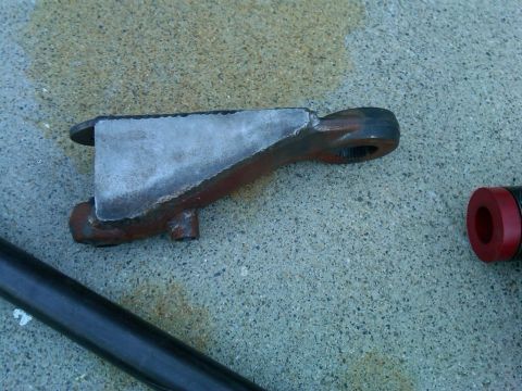 1986 Ford Bronco - A close-up view of a steering knuckle, possibly for an off-road vehicle, with a red bushing visible to the right.