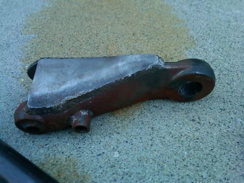 1986 Ford Bronco - A close-up view of a modified steering linkage component resting on a textured surface.
