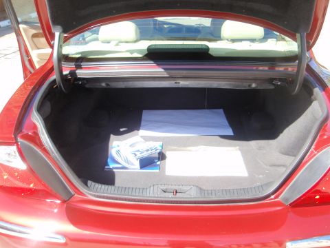 2000 Jaguar S-Type - The trunk of a red Jaguar S-Type is open, revealing a carpeted interior with some documents and papers laid out.