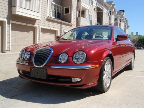 2000 Jaguar S-Type - A red Jaguar S-Type is parked in front of a residential building with garages.
