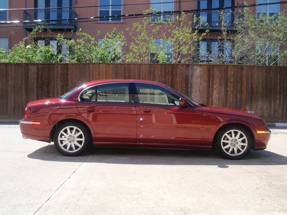 Red 2000 Jaguar S-Type sedan, side view, parked on concrete