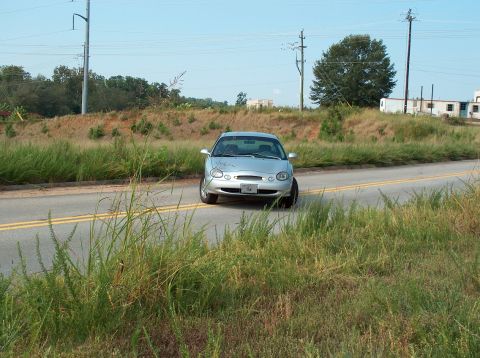 1998 Ford Taurus - Silver 1998 Ford Taurus seen from the front on a road with tall grass.