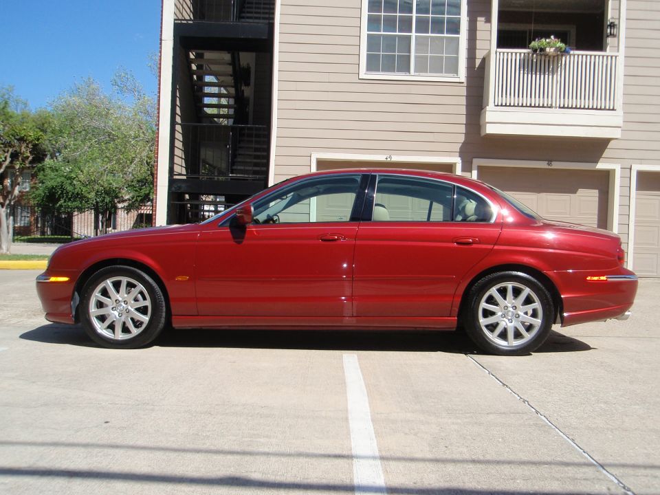 Red 2000 Jaguar S-Type sedan parked on concrete, side view