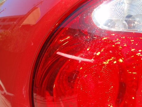 2000 Jaguar S-Type - Close-up of a red car tail light showing scratches and dirt. The vehicle's year is not discernible from this view.