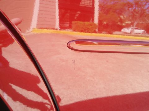 2000 Jaguar S-Type - A close-up of a red car's hood shows a chrome trim piece and a reflection of another vehicle.