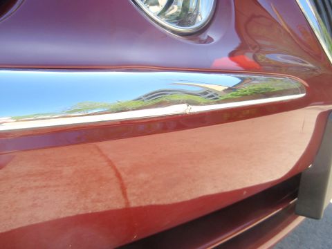 2000 Jaguar S-Type - Close-up of a red car's front end, showing chrome trim and part of a headlight.