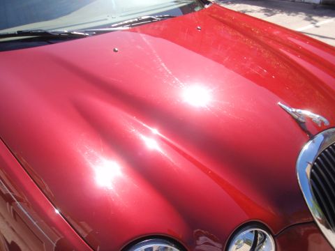 2000 Jaguar S-Type - Front view of a red Jaguar S-Type showing the hood ornament and grille detail.