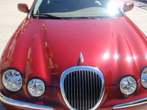 2000 Jaguar S-Type - The distinctive grille and hood ornament of a red Jaguar S-Type are visible in this front-facing shot.