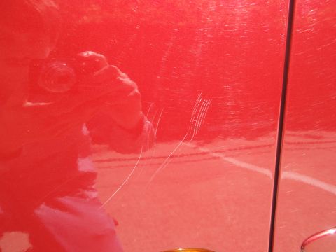 2000 Jaguar S-Type - Scratches mar the red paint of a car door, obscuring any identifying details.