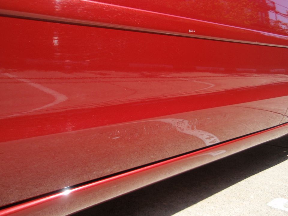 Close-up of a red car's lower door panel and rocker trim