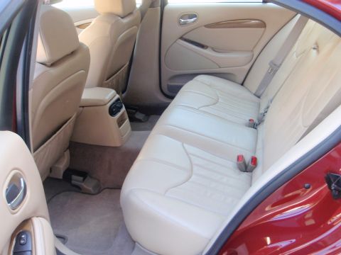 2000 Jaguar S-Type - Interior view of a red Jaguar S-Type, showing tan leather seats and rear climate controls.