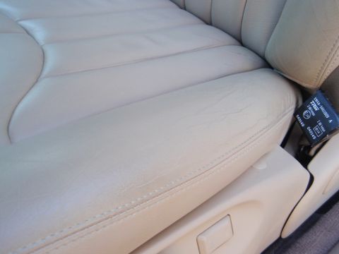 2000 Jaguar S-Type - The interior of a car shows a close-up view of a tan leather seat and seatbelt.