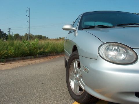 1998 Ford Taurus - Front corner view of a silver 1998 Ford Taurus on a paved road with vegetation and utility lines.