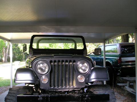 1978 Ford Bronco - A dark gray Jeep CJ-5 is parked in front of a green Ford Bronco under a carport.