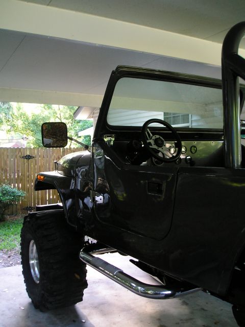 1978 Ford Bronco - Side view of a dark Jeep CJ showing its interior and large tires.