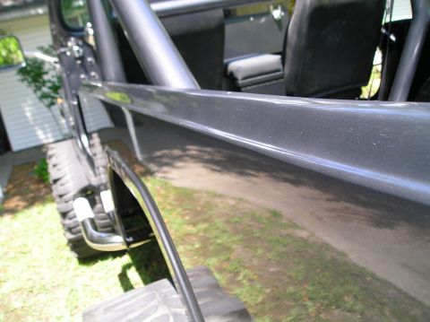 1978 Ford Bronco - Interior view of a dark grey SUV with a roll cage and black seats, showing a close-up of the side panel.