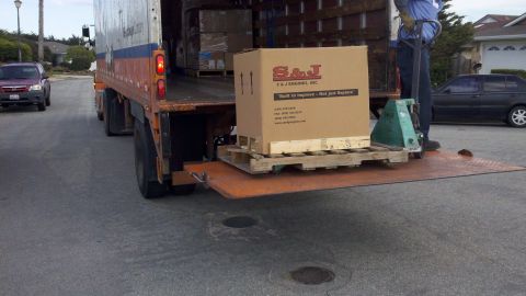 1978 Ford Bronco - A box from S&J ENGINES, INC. is being unloaded from a delivery truck, with another vehicle visible in the background.