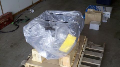 1978 Ford Bronco - Engine covered in plastic wrap on a wooden pallet, with boxes in the background.