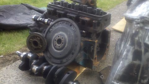 1978 Ford Bronco - Engine block, crankshaft, and other engine parts are disassembled and laid out on the ground.