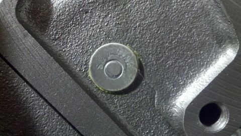 1978 Ford Bronco - A close-up view of a metal engine component with a bolt head visible.