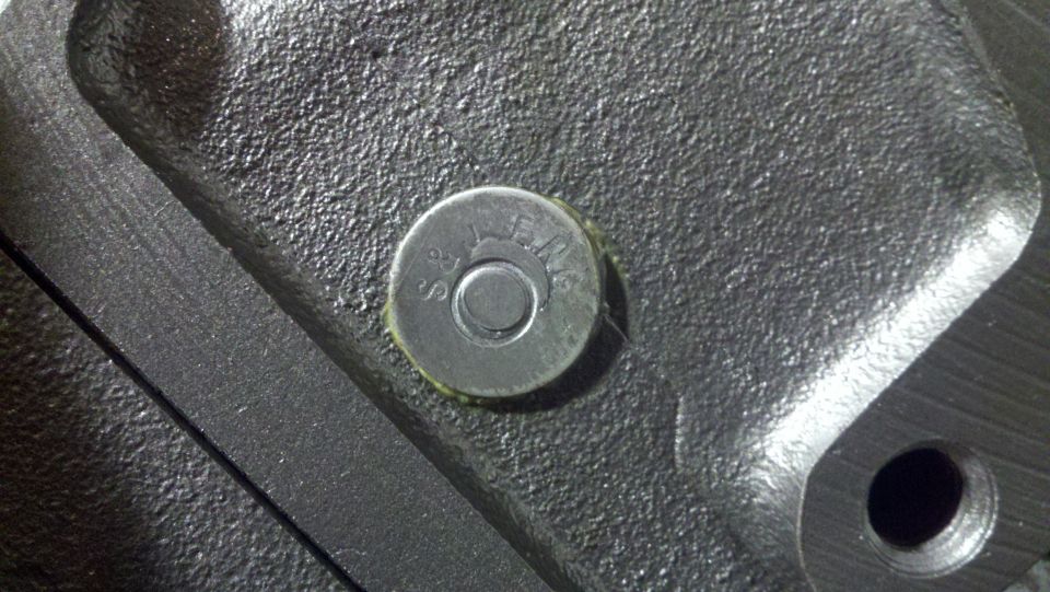 Close-up of a metal engine part with a bolt head showing some text