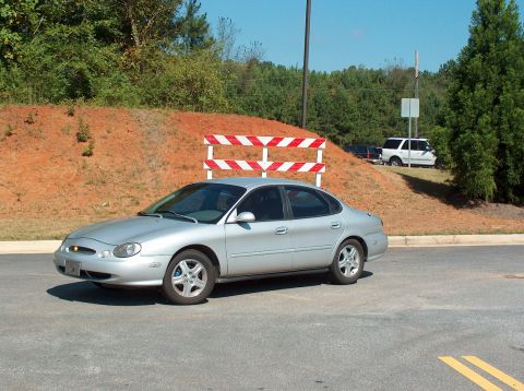 1998 Ford Taurus - Silver 1998 Ford Taurus seen parked outdoors near a construction barrier.