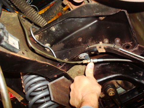 1995 Ford Bronco - A hand points to a brake line connection, part of the vehicle's braking system.