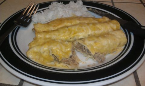 1989 Ford Bronco - A plate of enchiladas served with rice, accompanied by a fork and knife.