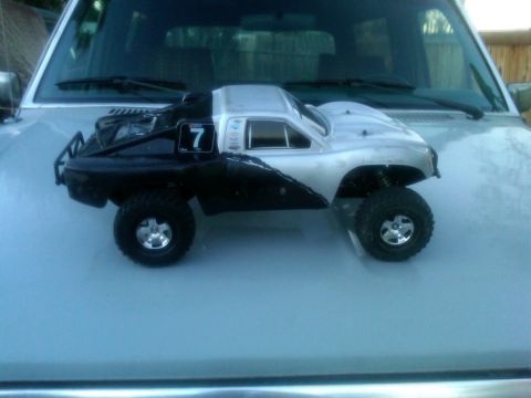 1986 Ford Bronco - A remote control monster truck is placed on the hood of a light-colored SUV.