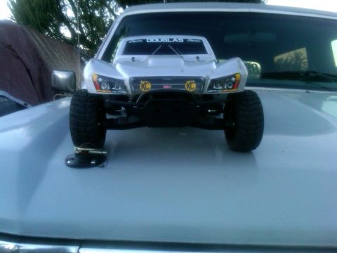 1986 Ford Bronco - A remote control truck is placed on the hood of a larger vehicle, with 'KC' lights and 'DOUGLAS' visible on its body.