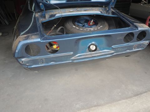 1973 Chevrolet Camaro - The rear of a blue 1970s era car is shown with the trunk open, revealing a spare tire and electrical components.