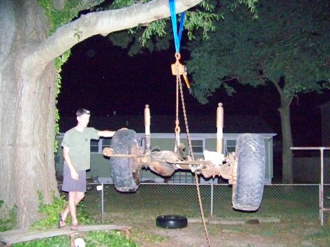 1985 Ford Bronco - A person stands near a vehicle axle assembly suspended by a chain hoist from a tree.