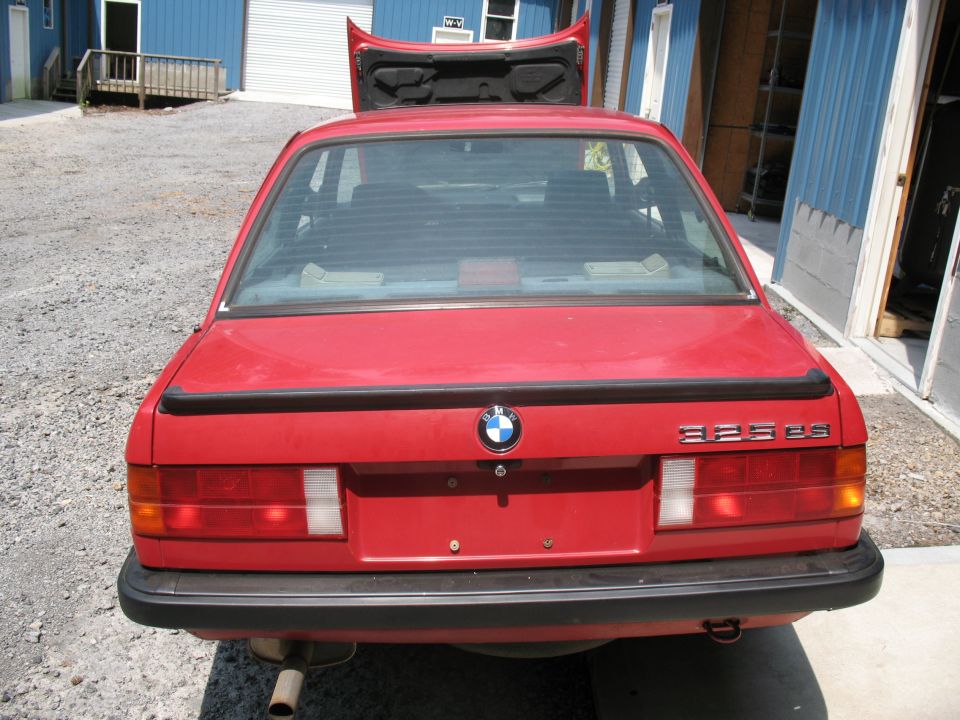 Red BMW E30 325es sedan with trunk open, rear view. Badge reads 325es