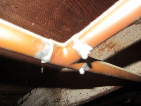 1968 Ford Mustang - This image shows copper pipes with visible leaks and solder joints, situated beneath wooden beams.