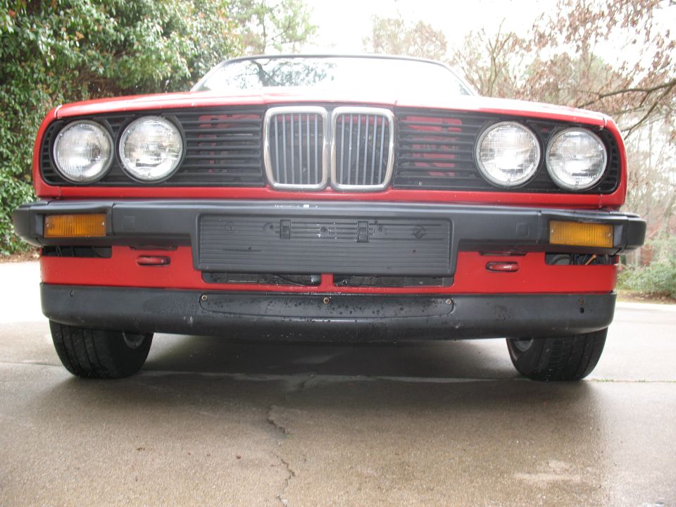 Red 1986 BMW 3 Series front end with dual headlights and grille