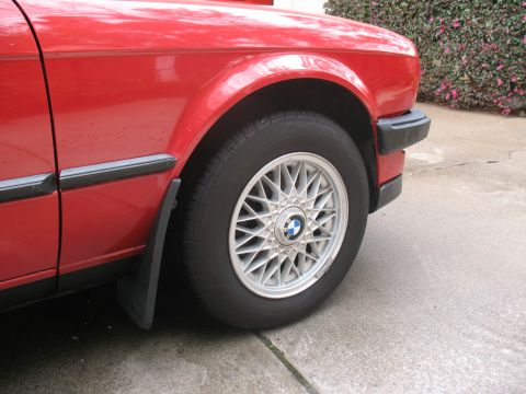 1986 BMW 3 Series - Close-up of the front fender and wheel of a red 1986 BMW 3 Series.