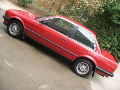 1986 BMW 3 Series - A red 1986 BMW 3 Series coupe is shown from a 3/4 front angle, parked on a paved surface.