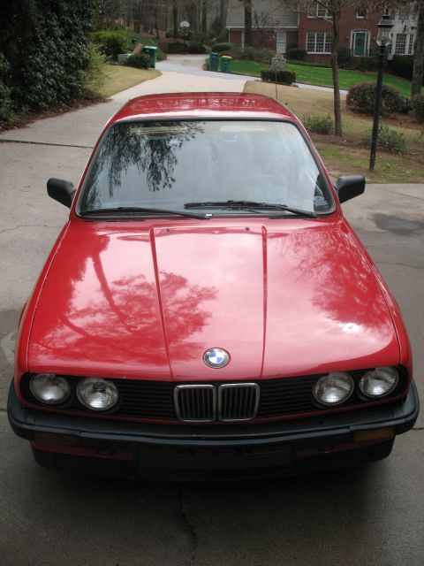 1986 BMW 3 Series - Front view of a red 1986 BMW 3 Series sedan with its iconic grille and headlights visible.