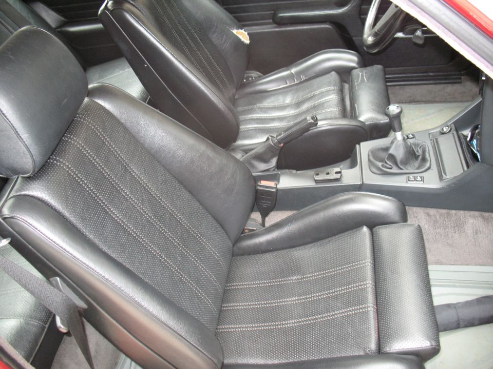 Interior of a 1986 BMW 3 Series with black cloth and leather seats and manual shifter