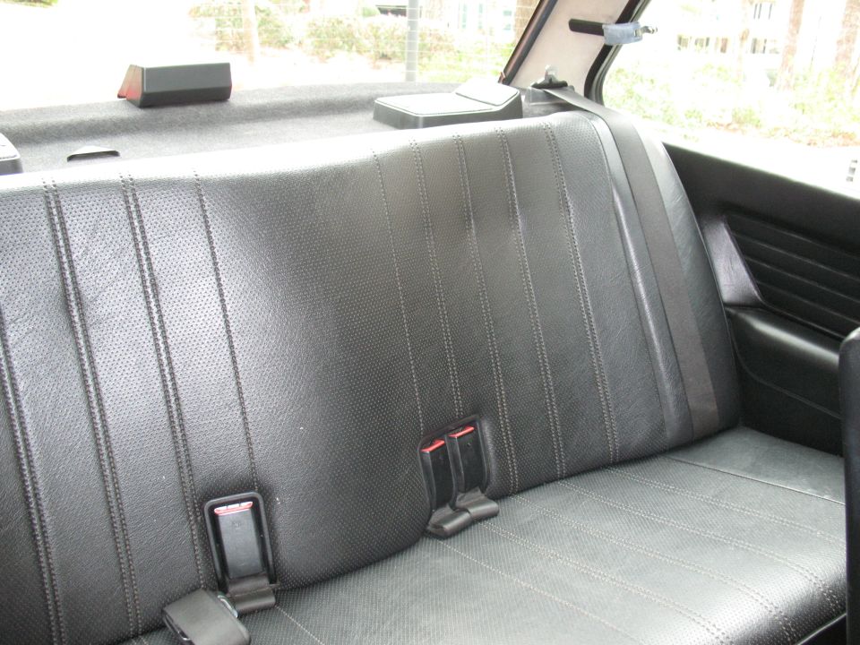 Rear seat interior with black perforated leather seats and seatbelts