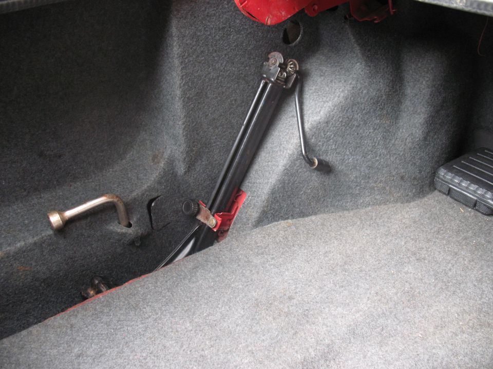 Car jack and lug wrench stored in trunk compartment