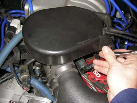 1990 Ford Bronco - Close-up of a hand working on an engine bay, focusing on the ignition system.
