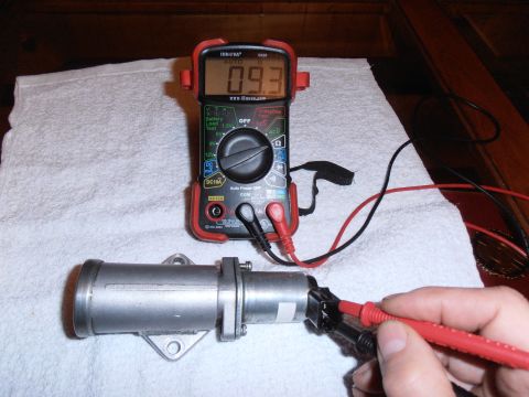 1990 Ford Bronco - A multimeter measures the resistance of a silver automotive part, displaying a reading of 0.93.