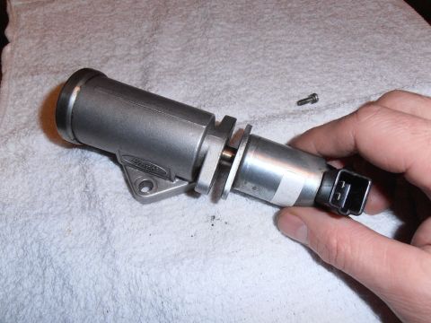 1990 Ford Bronco - A hand holds a metal Idle Air Control Valve with a Ford logo, resting on a white cloth.